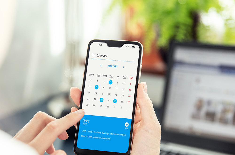 Businesswoman points smartphone screen and checks calendar on application. Application on screen created in graphic program